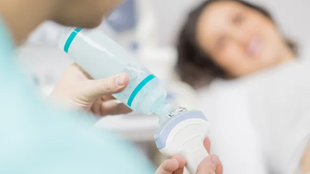 Ultrasonido de senos: doctora aplicandole gel al escanner